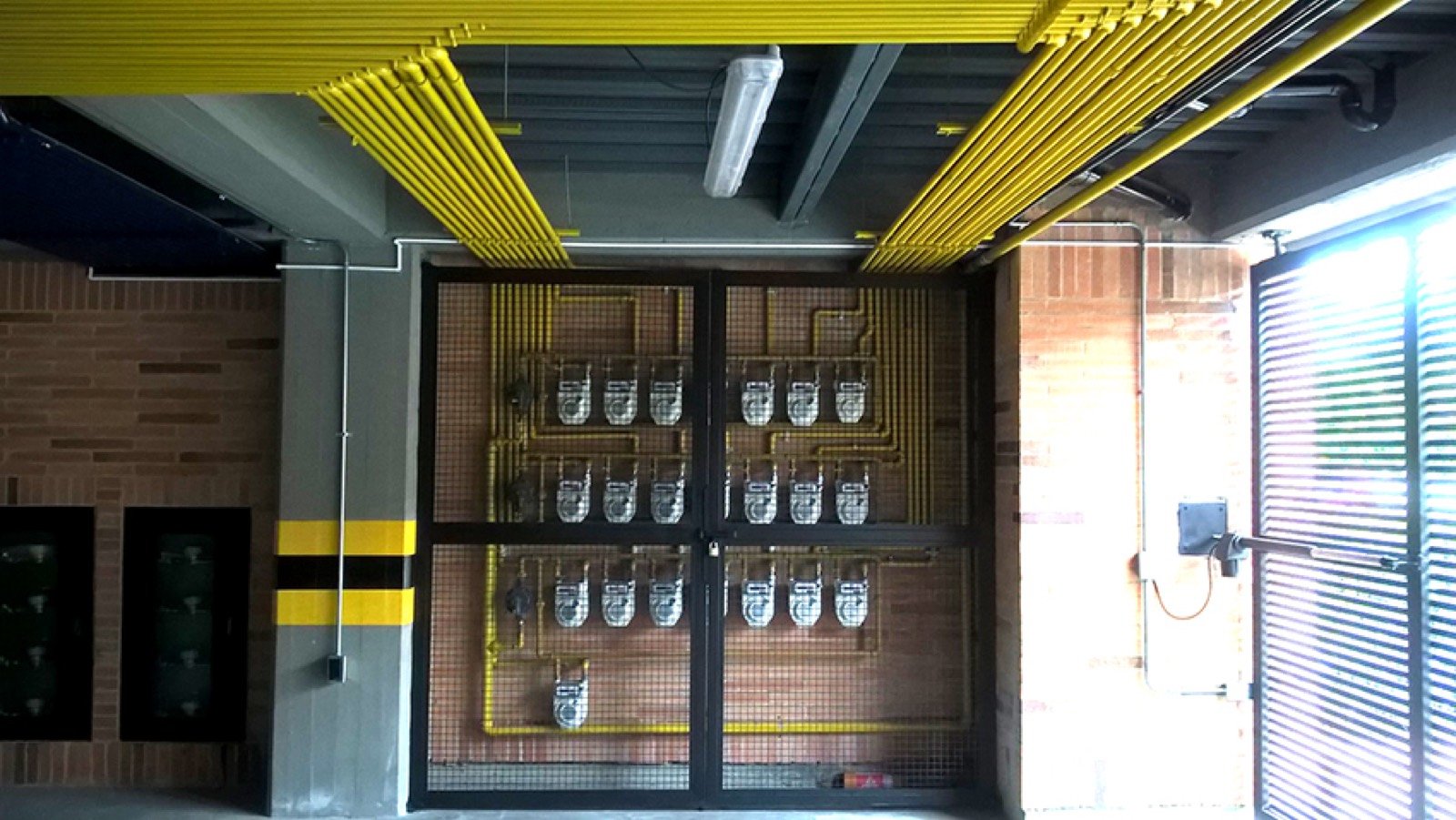 Cuarto de medidores de gas con tubería amarilla en edificio residencial